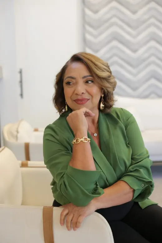 Cristina Marinho sorrindo, com a mão apoiada no queixo, na recepção da clínica